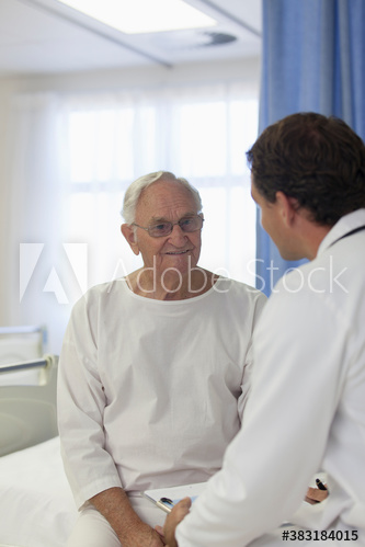 Smiling male senior patient talking with doctor in hospital room