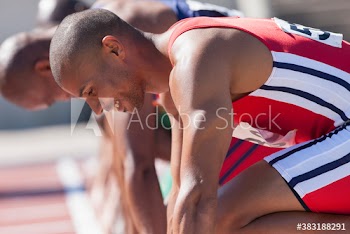 Smiling male track and field sprinter ready at starting line