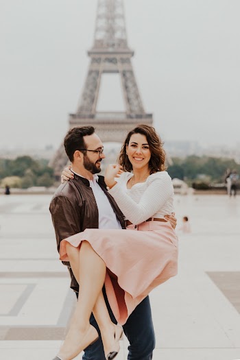 Smiling Man Carrying Smiling Woman Near Eiffel Tower In Paris France
