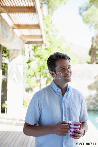 Smiling man drinking coffee on patio