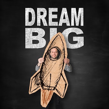 Smiling man holding sketch of a rocket drawn on brown crumpled paper...