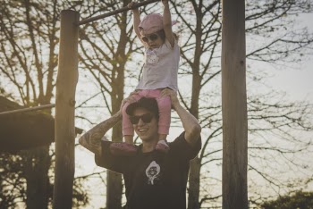 Smiling Man in Black Holds Toddler over Shoulder
