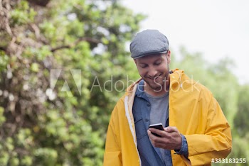 Smiling man in raincoat using smart phone