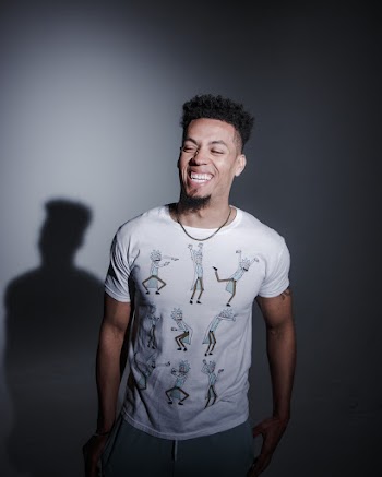 Smiling Man in White Crew Neck T-shirt Standing in Dark Room