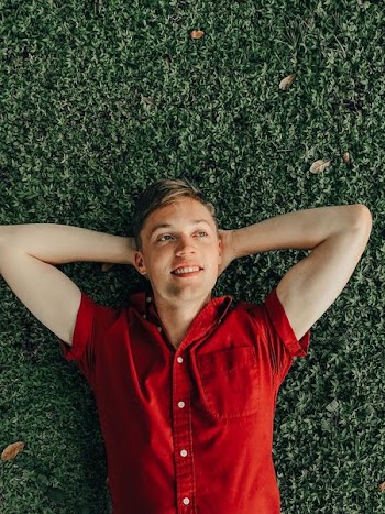 smiling man laying on green grass