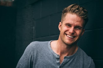 smiling man standing beside blue painted wall