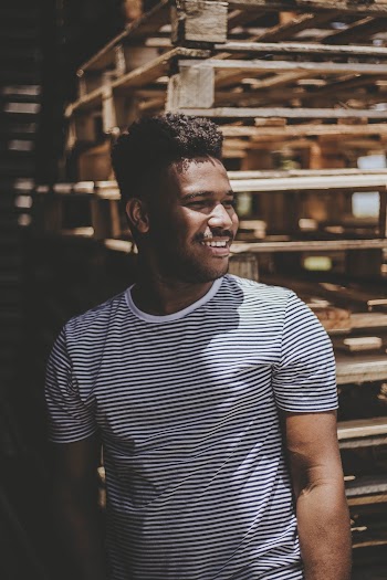Smiling Man Standing Front Pile of Palette