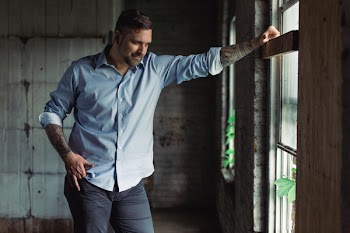 Smiling Man Standing Near Window Looking Straight