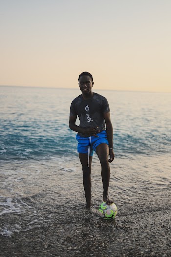 Smiling Man Standing on Seashore With Ball