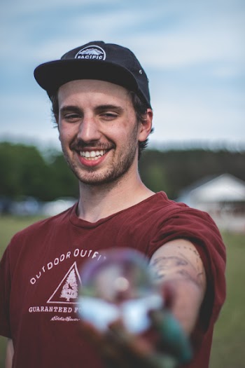 Smiling Man Wearing Maroon Shirt and Black Cap