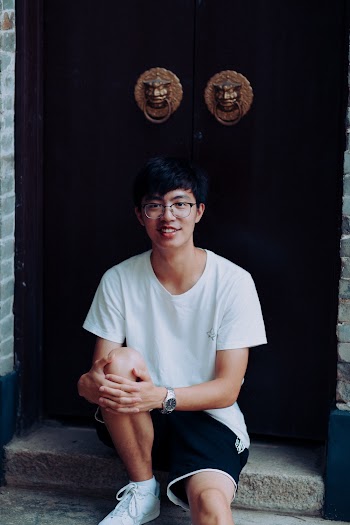 Smiling Man Wearing White Shirt Sitting on Concrete Surface