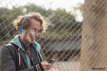 Smiling man with headphones and mp3 player listening to music at fence