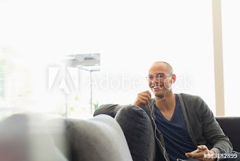 Smiling man with headphones and smart phone on sofa