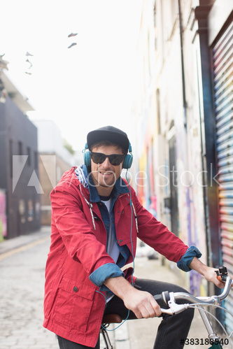 Smiling man with headphones and sunglasses on bicycle