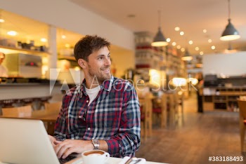 Smiling man working at laptop in cafe