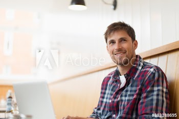 Smiling man working at laptop in cafe