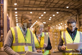 Smiling managers with paperwork in distribution warehouse