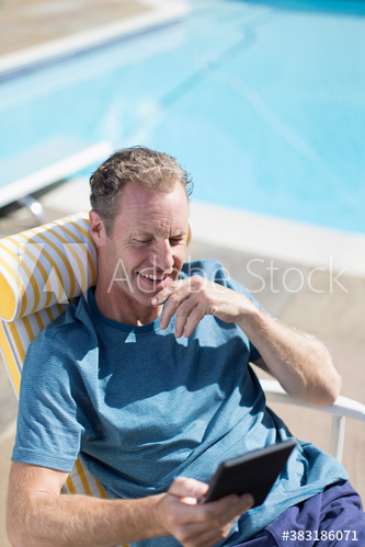Smiling mature man using smart phone at sunny poolside