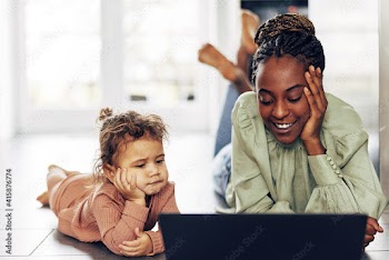 Smiling mom watching something on a laptop with her little daughter