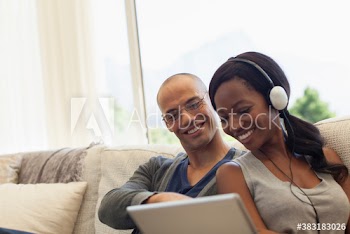 Smiling multiethnic couple using digital tablet on sofa