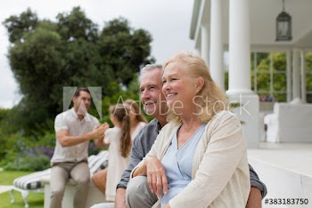 Smiling senior couple relaxing on patio with family