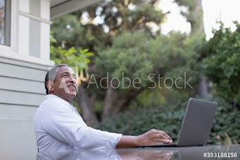 Smiling senior man using laptop on patio