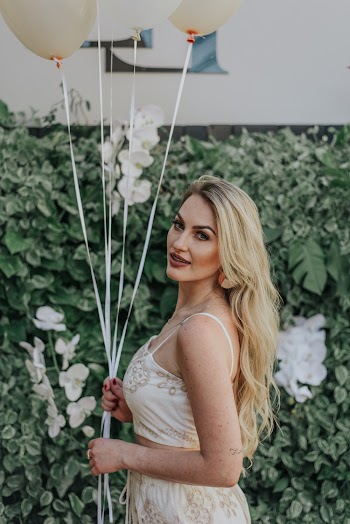 Smiling Woman Holding Balloons Near Green-leafed Plants