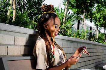 Smiling Woman Holding Gray Smartphone Sitting on Brown Wooden Bench