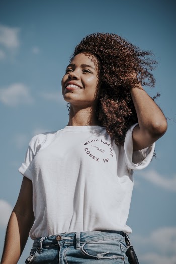Smiling Woman Holding Her Hair Under Blue Sky