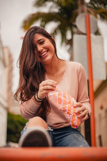 Smiling Woman Holding White and Orange Plastic Pack