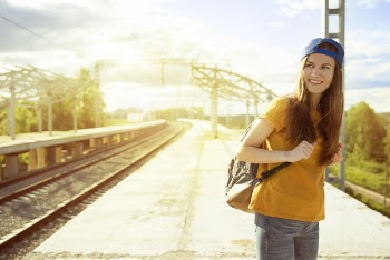 Smiling Woman in Orange T Shirt and Blue Snap Back Cap Carrying Backpack