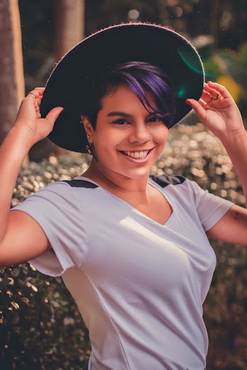 Smiling Woman in White T-shirt Holding Her Cap