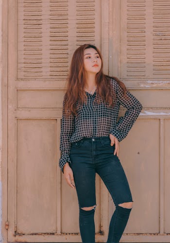 Smiling Woman Leaning on Wall While Holding Her Waist