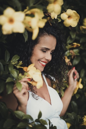 Smiling Woman Leaning on Yellow Bell Flower