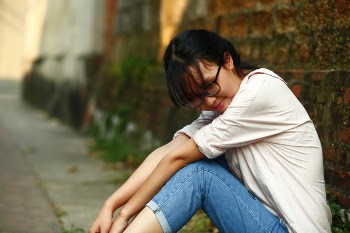 Smiling Woman Sitting Beside Bricked Brown Wall