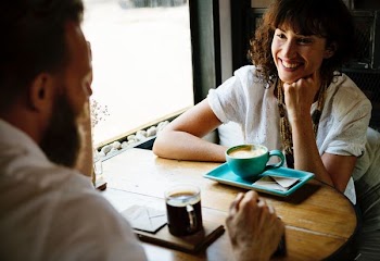 smiling woman sitting front of man near window