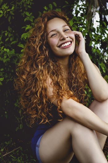 Smiling Woman Sitting in Front of Green-leaf Plants