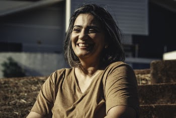 Smiling Woman Sitting on Brown Staircase Outdoor