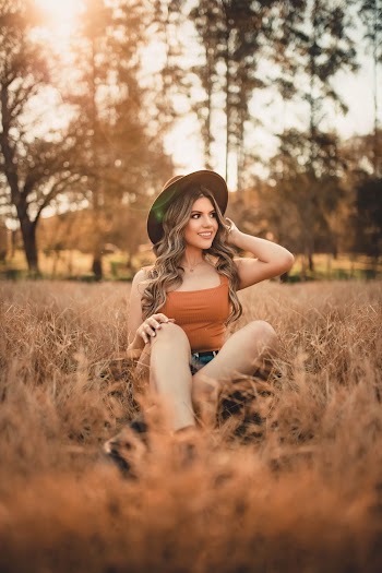 Smiling Woman Sitting on Grass during Golden Hour