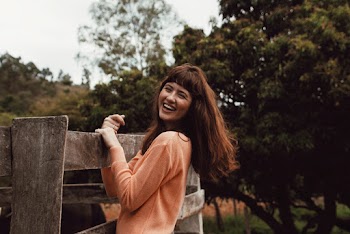 Smiling Woman Standing and Holding Wooden Fence