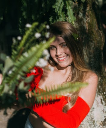 Smiling Woman Standing Behind Fern Plant