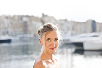 Smiling Woman Standing Near Body of Water Under Blue Sky