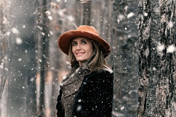 Smiling Woman Standing Near Tree With Snow Falling