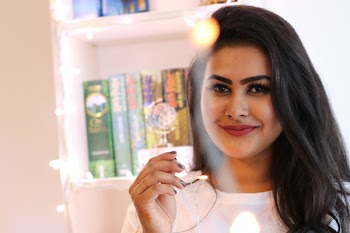 Smiling Woman Standing Near Wooden Cabinet Holding Lighted String Lights