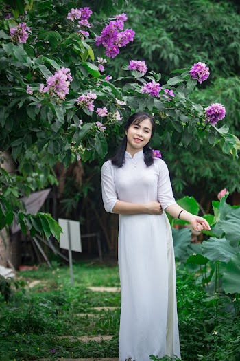 Smiling Woman Standing Under Purple Flowering Plant