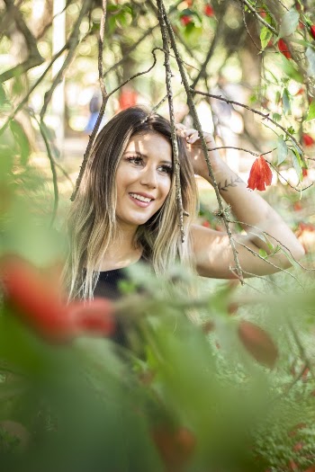 Smiling Woman Standing Under Red Flowered Tree