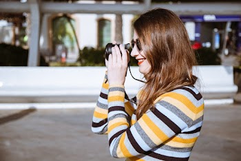 Smiling Woman Taking S Hot With Camera Beside White Building