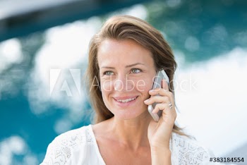 Smiling woman talking on smart phone at poolside