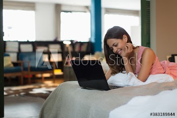 Smiling woman using laptop on bed