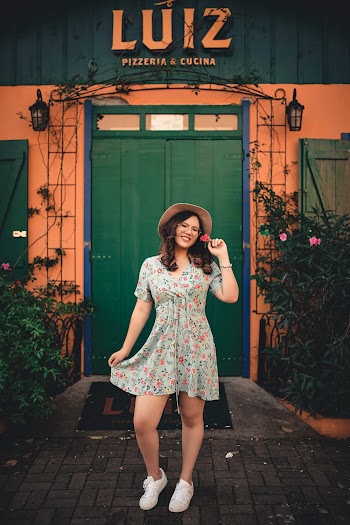 Smiling Woman Wearing a Floral Dress Posing Infront of a Building 